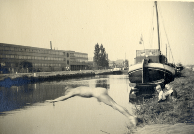 825427 Afbeelding van een jongen die een duik neemt in het Merwedekanaal te Utrecht, vanaf de Merwedekade, met links ...
